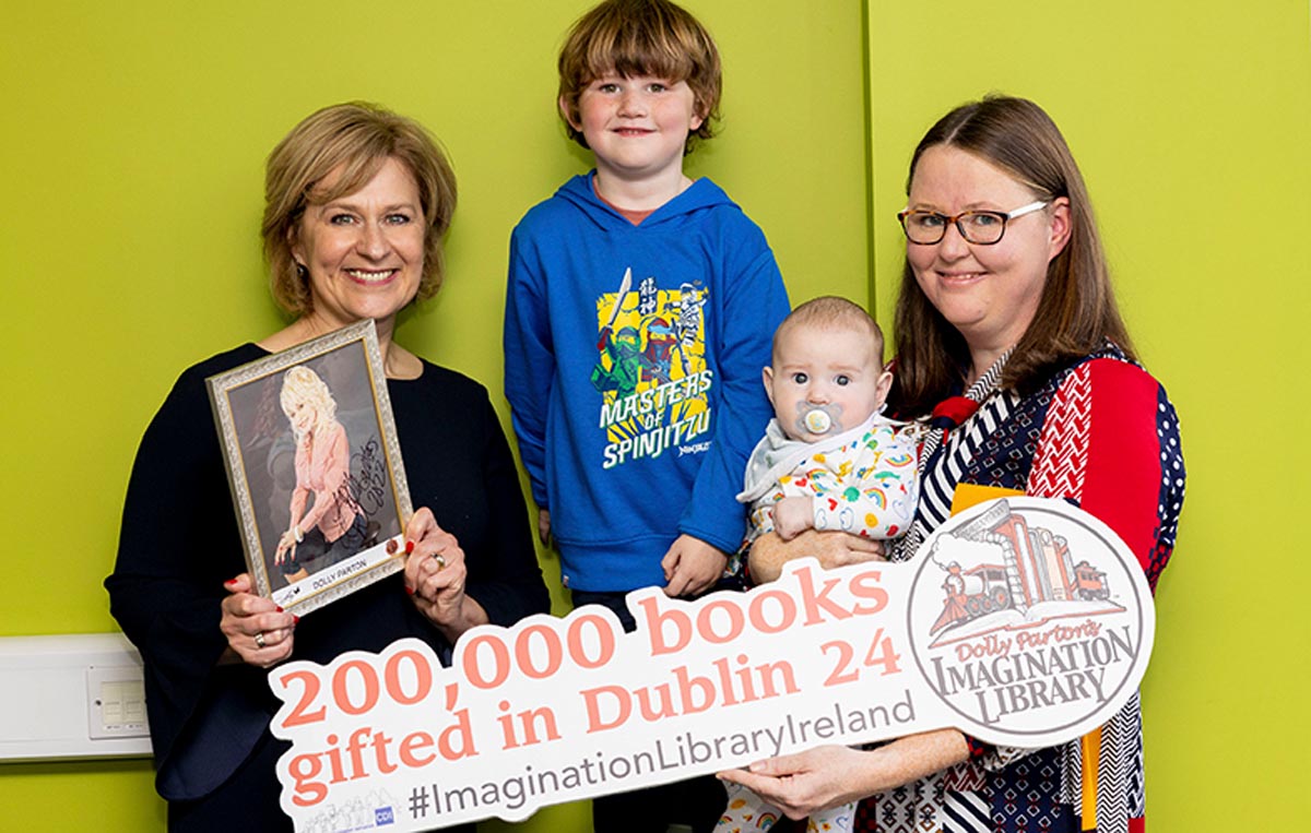 Two women and two children with a sign celebrating 200,000 books being gifted in Dublin 24 from Dolly parton Imagination library